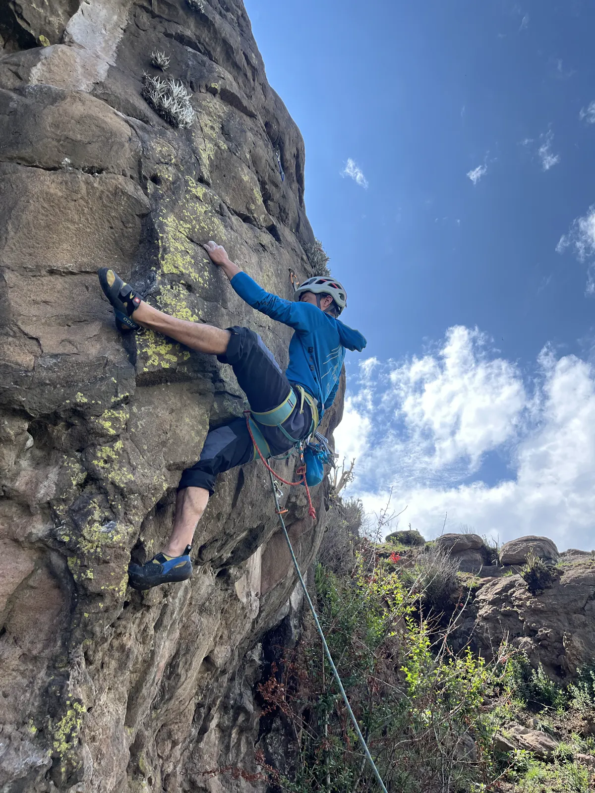 Escalador con cuerda en la pared de roca de Calixtlahuaca, contra el cielo.