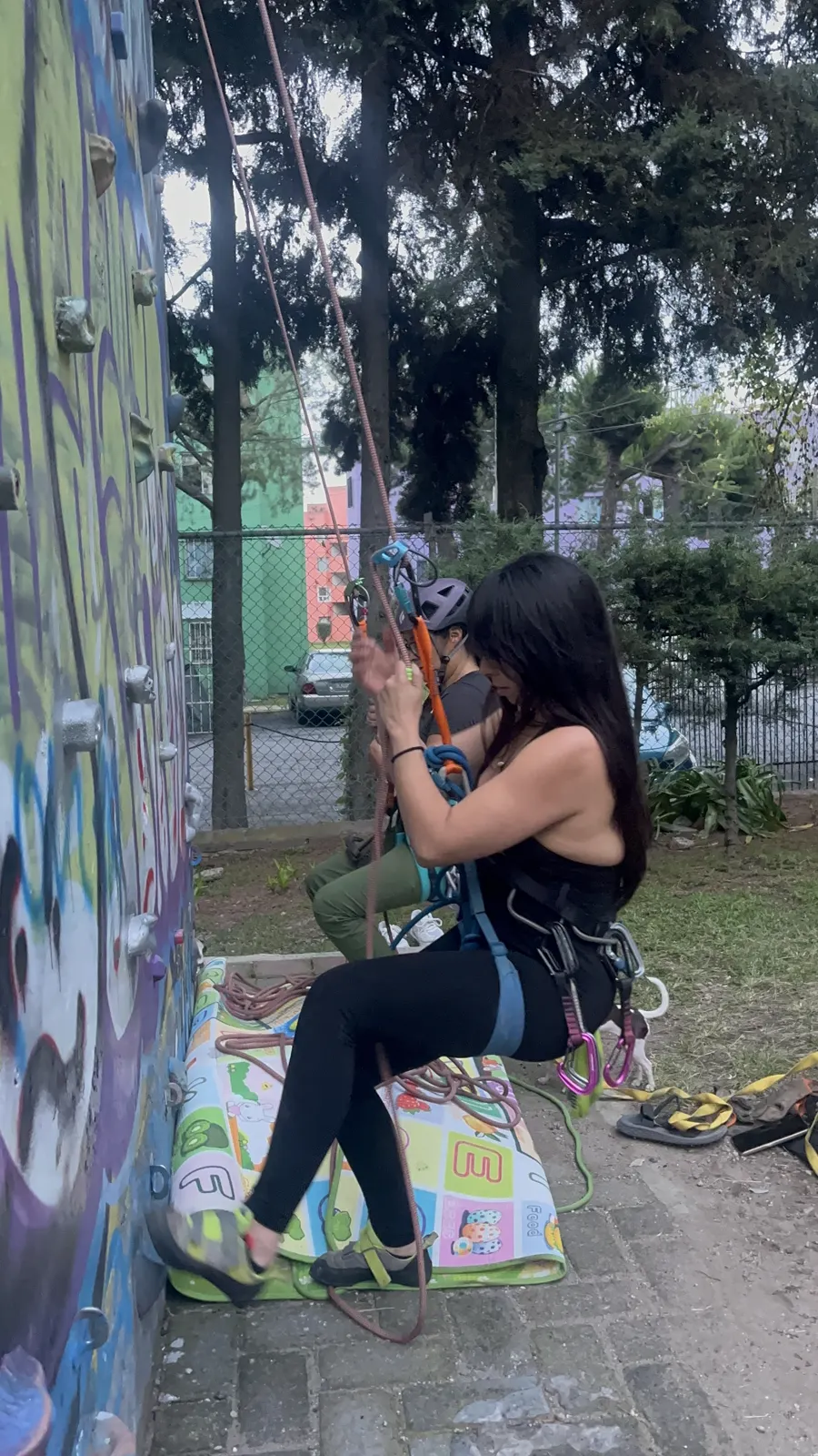 Escaladora con arnés sentada al pie del muro del Parque La Loma.