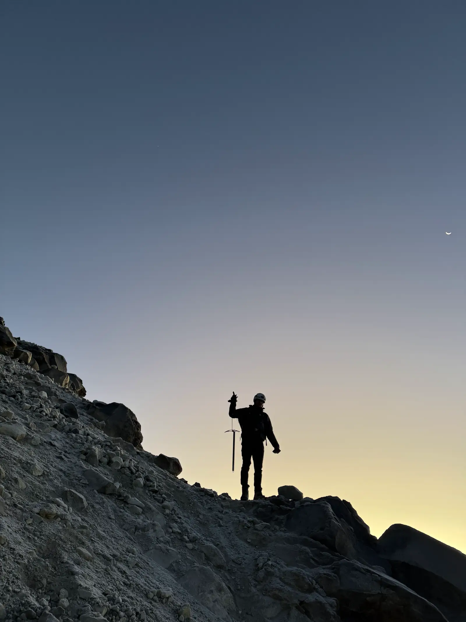 Silueta al amanecer con los brazos arriba en la ladera del volcán.