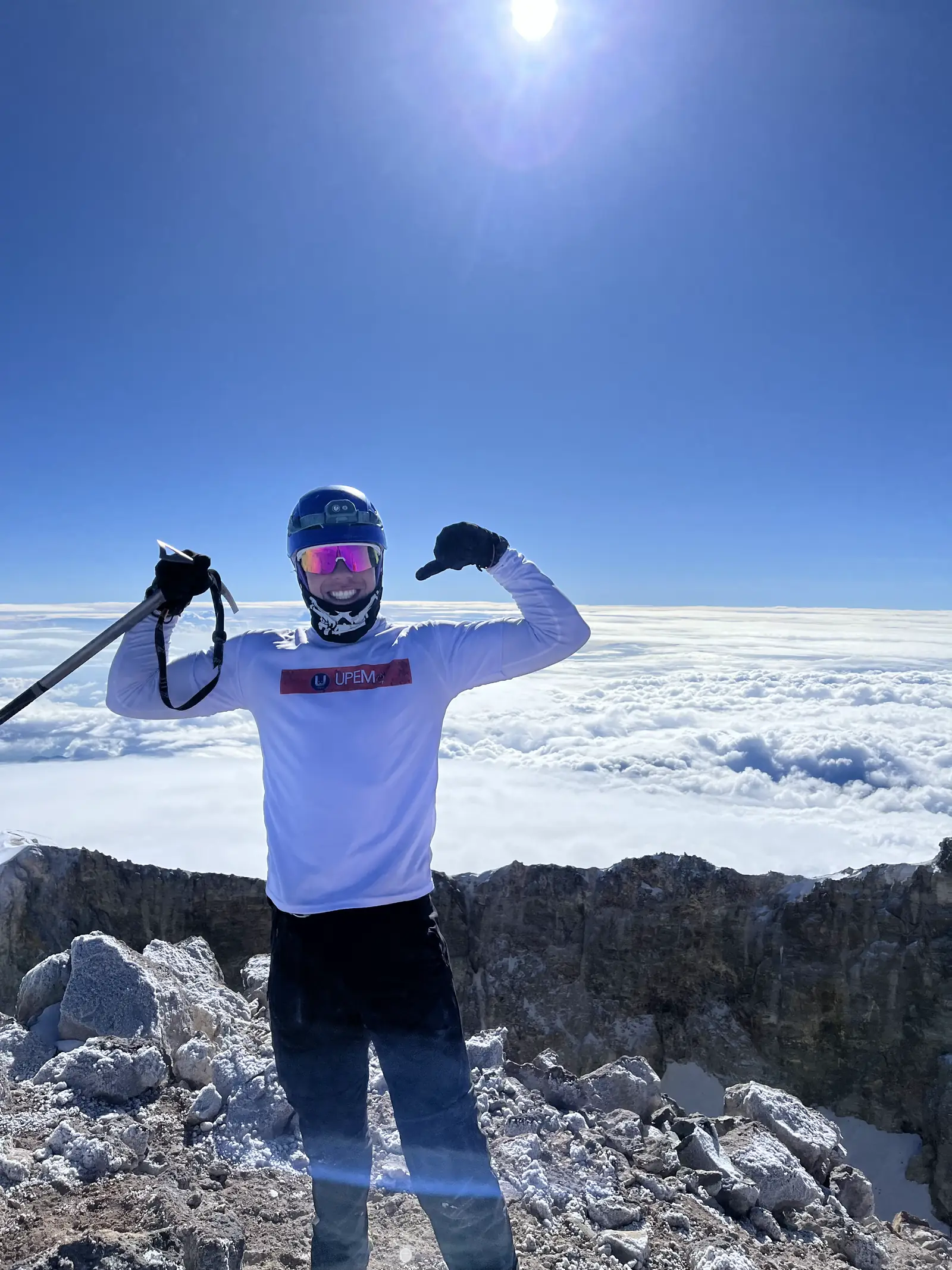 Montañista con piolet en la cumbre del Pico de Orizaba, sobre el mar de nubes.