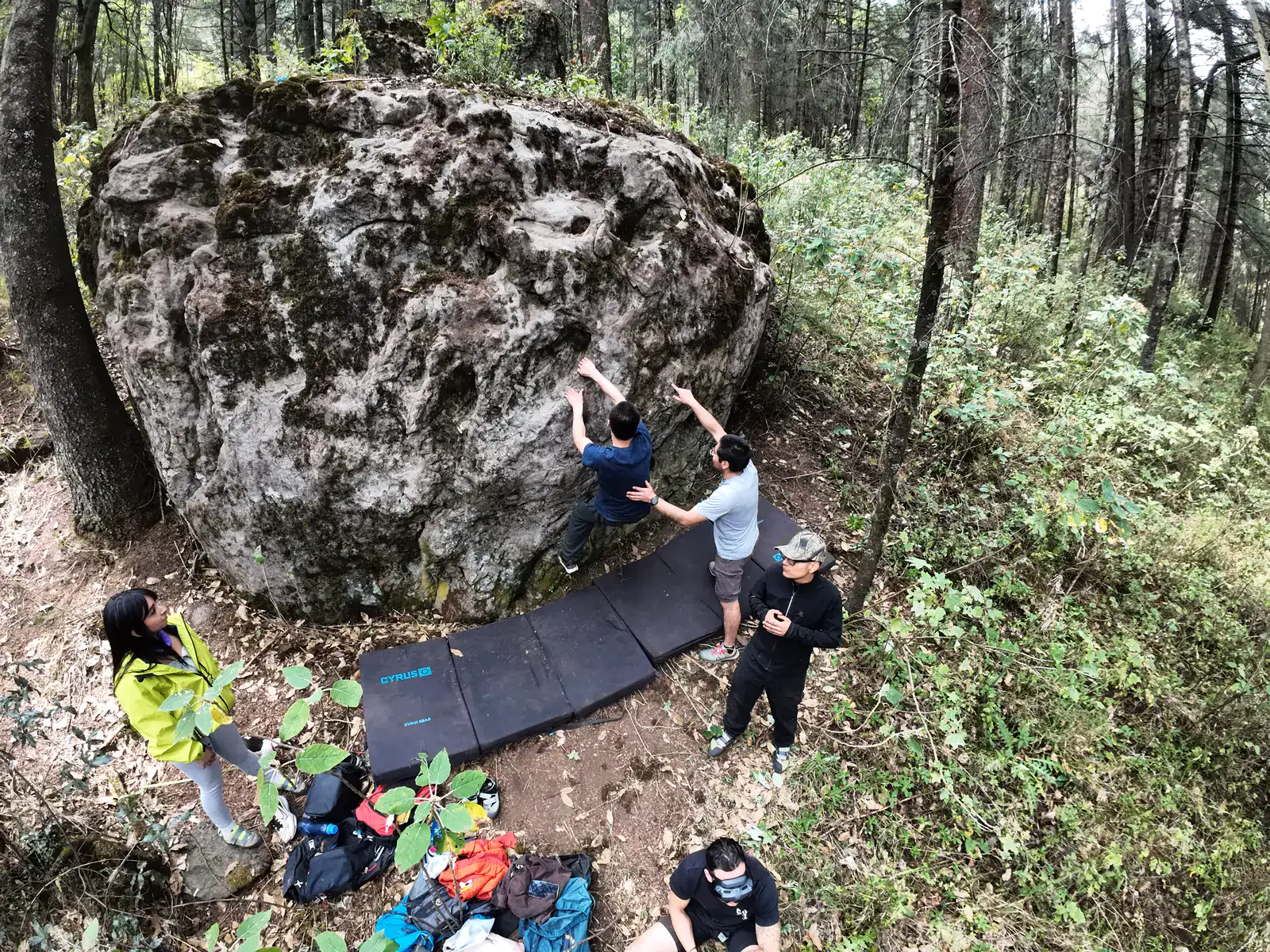 Grupo aprendiendo a escalar un bloque de roca en el bosque.