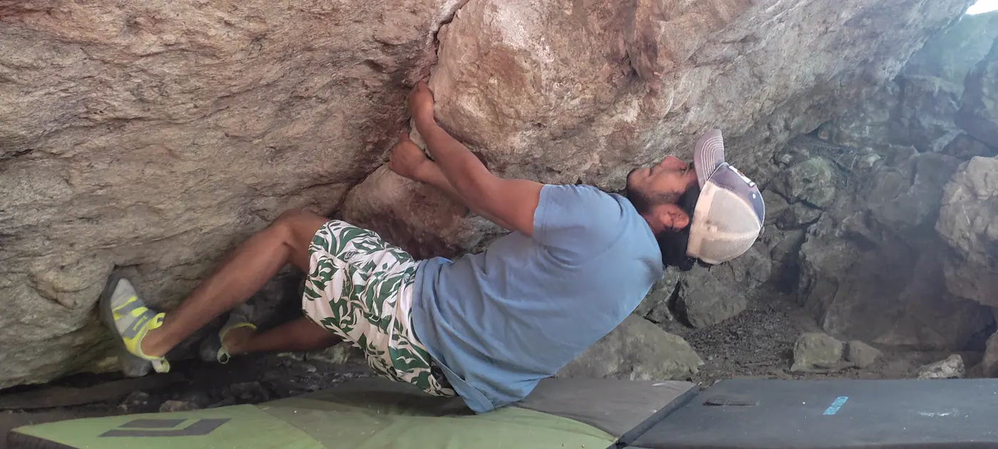 Escalador colgado del techo de un bloque de roca.